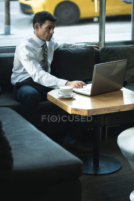 Homme d'affaires utilisant un ordinateur portable à la table dans le hall de l'hôtel — Photo de stock