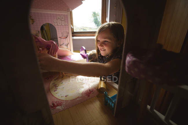 Дівчинка, граючи з ляльковий будиночок в спальні в домашніх умовах — стокове фото