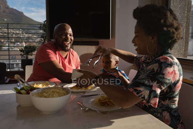 Mãe servindo comida para a família na mesa de jantar em casa . — Fotografia de Stock