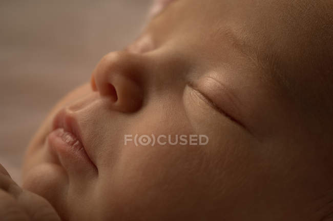 Close-up of face of newborn baby sleeping on baby bed. — Stock Photo