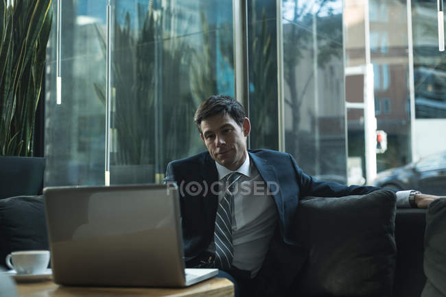 Businessman using laptop in office lobby — Stock Photo