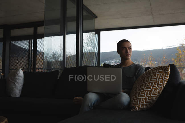 Молодой человек использует ноутбук в гостиной дома — стоковое фото