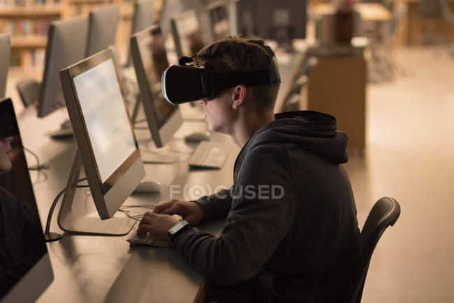 Teenage boy using virtual reality headset while studying in computer class at university — Stock Photo