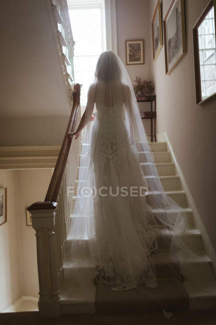 Vue arrière de la mariée montant l'escalier à la maison — Photo de stock