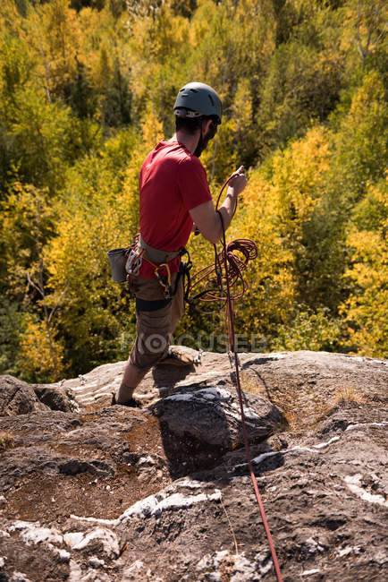 Турист собирает веревку, стоя на горе в лесу — стоковое фото