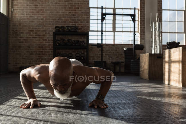 Determined senior man doing push up in fitness studio. — Stock Photo