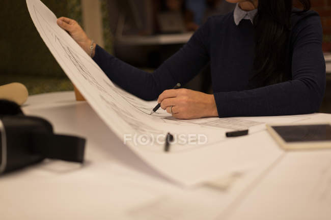 Mid section of female looking at blueprint in office — Stock Photo