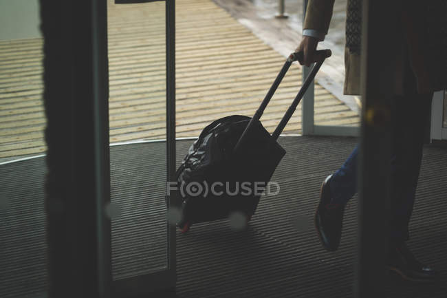 Uomo d'affari in arrivo in hotel con trolley bag — Foto stock