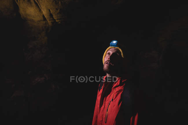 Randonneur debout à l'intérieur de la caverne sombre portant la torche avec sac à dos — Photo de stock