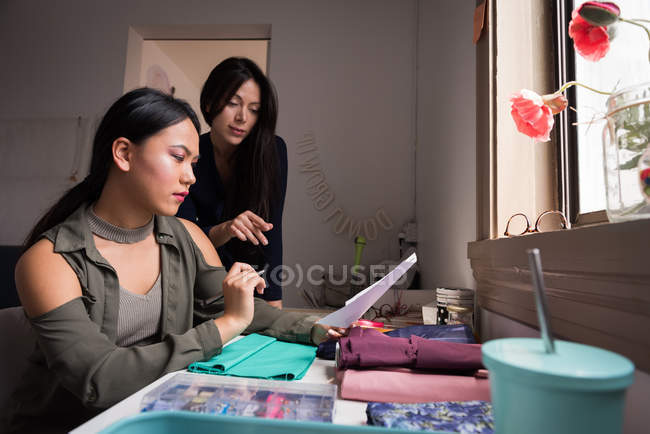 Design de moda discutindo sobre amostras de tecido em estúdio . — Fotografia de Stock