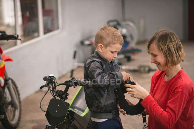Матері, підготовка її син їздою на велосипеді в гаражі — стокове фото