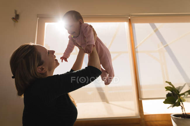 Madre che gioca e solleva il bambino a casa . — Foto stock
