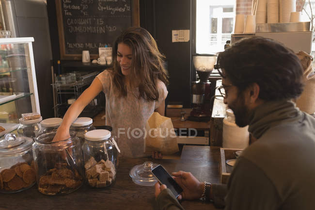 Waitress Packing Sweet Food In Paper Bag At Counter In Coffee Shop