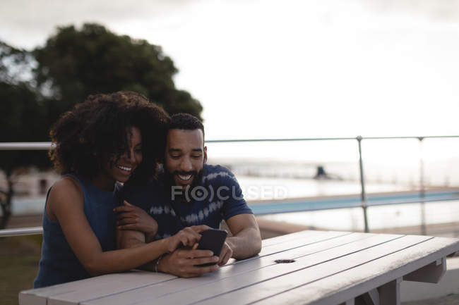 Пара с помощью мобильного телефона на набережной в солнечный день — стоковое фото