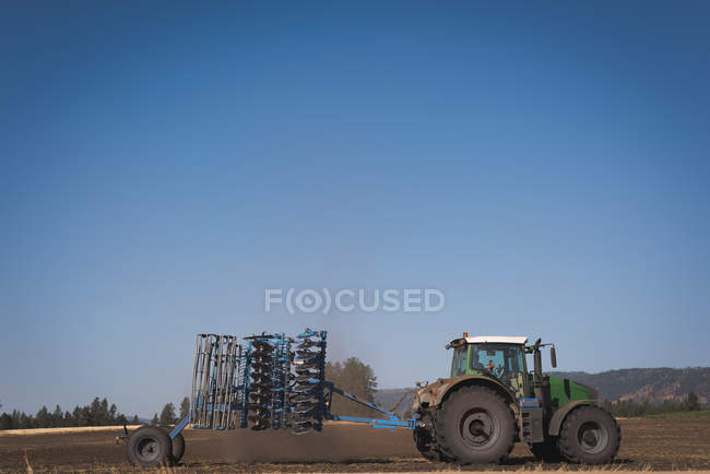 Trattore aspersione fertilizzante in campo in una giornata di sole — Foto stock