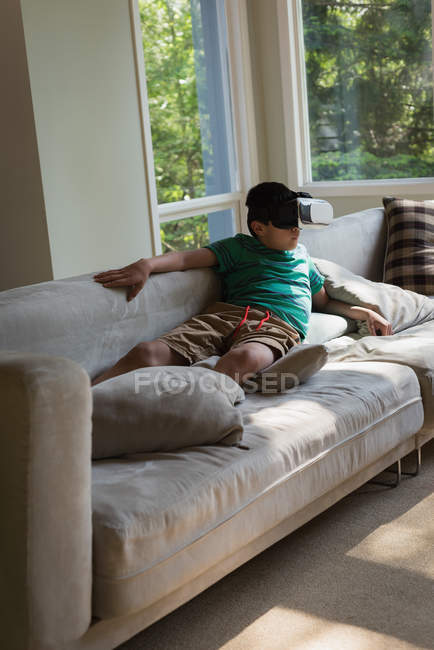 Хлопчик за допомогою віртуальної реальності гарнітуру у вітальні на дому — стокове фото