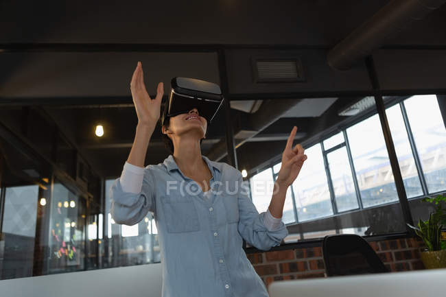 Donna d'affari che sperimenta cuffia realtà virtuale in ufficio . — Foto stock