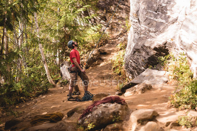 Escursionista che si prepara a scalare la montagna rocciosa nella foresta — Foto stock
