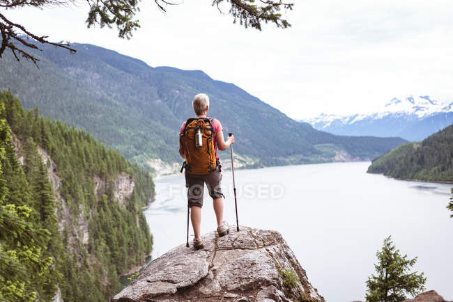 Rückansicht einer reifen Frau, die auf einem Felsen steht und auf den schönen Berg blickt — Stockfoto