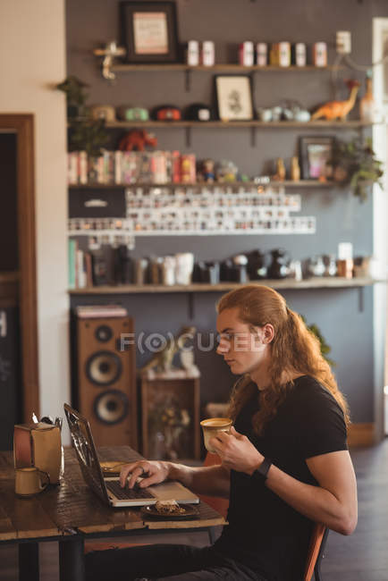 Людина, використовуючи ноутбук під час за кавою в кафе — стокове фото