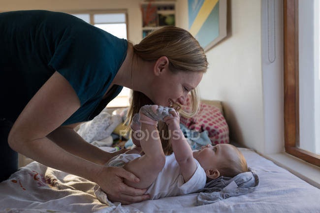 Feliz madre jugando con el bebé hijo en casa - foto de stock