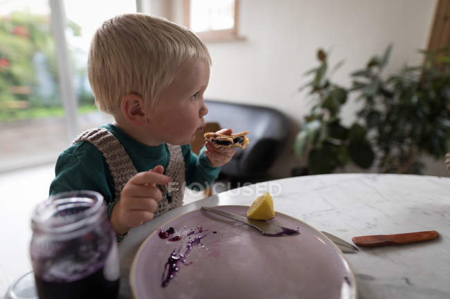 Boy having breakfast in living room at home. — Stock Photo