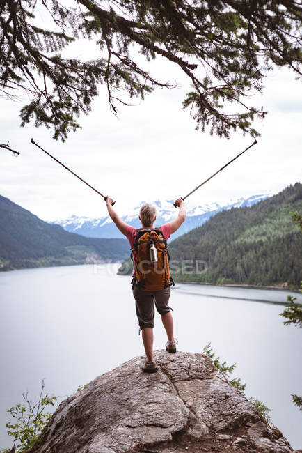 Vista trasera de la mujer madura de pie en la roca y mirando a la hermosa montaña - foto de stock