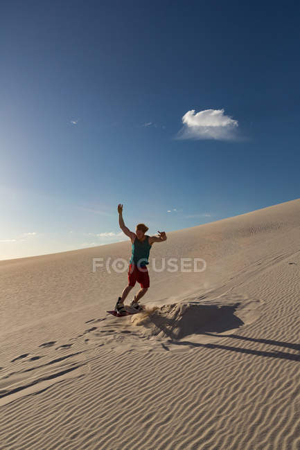 Sandboard homme sur dune de sable par une journée ensoleillée — Photo de stock