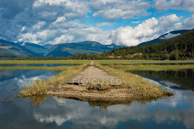 Pier in the river and green mountains in background — Stock Photo