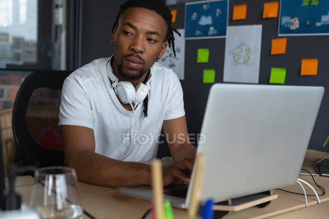Ejecutivo masculino usando el ordenador portátil en el escritorio en la oficina . - foto de stock