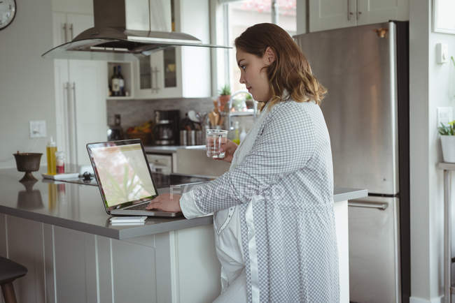 Беременная женщина работает дома на ноутбуке — стоковое фото