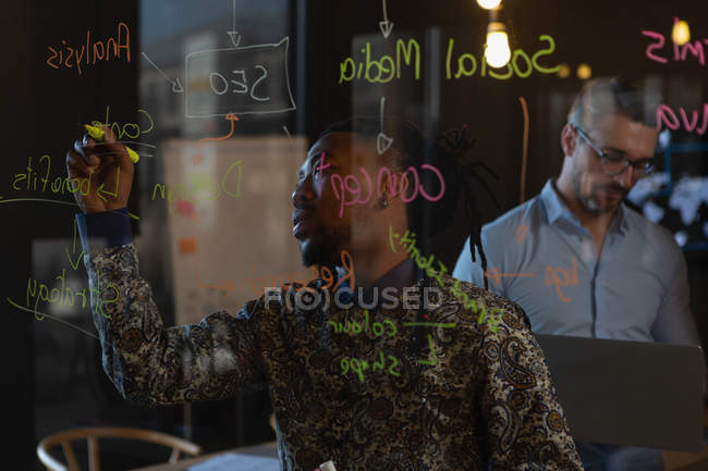 Dirigeants écrivant des notes sur le mur de verre dans le bureau . — Photo de stock