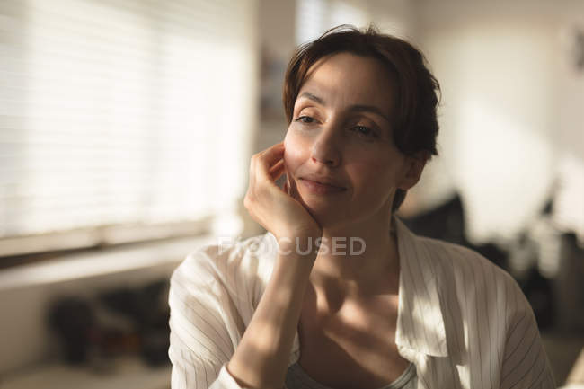 Close-up of young woman placing chin on hand looking away thoughtfully at home — Stock Photo