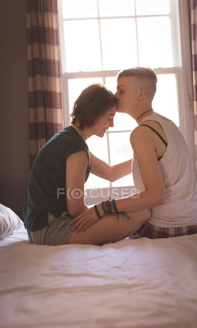 Жінка цілує дівчину на лобі в спальні вдома . — стокове фото