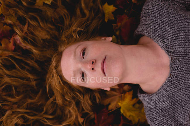 Крупним планом красива жінка лежить на сухому осінньому листі — стокове фото