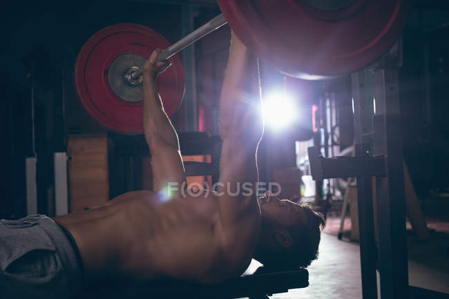 Homem musculoso exercitando com barbell no estúdio de fitness — Fotografia de Stock