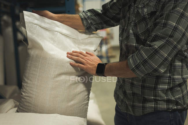 Середина людини, що регулює мішок зерна на заводі — стокове фото