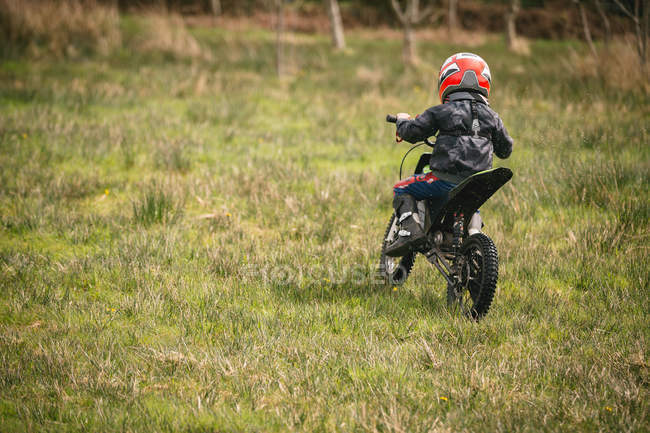 Rear view of kid riding a bike in garden — Stock Photo