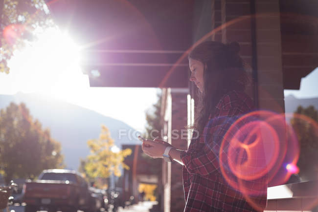 Женщина, использующая мобильный телефон возле кафе — стоковое фото