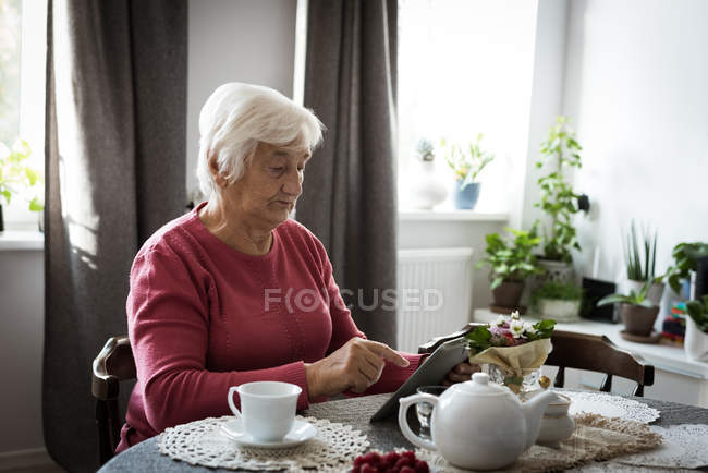 Femme âgée utilisant une tablette dans le salon à la maison — Photo de stock