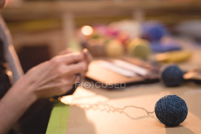 Frau im mittleren Abschnitt strickt Wolle in Schneiderei — Stockfoto