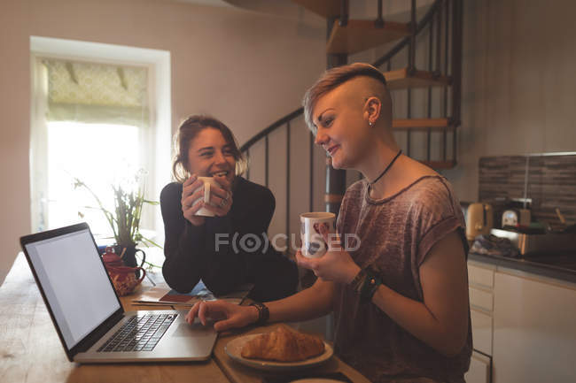 Лесбійську пару, використовуючи ноутбук під час вдома за кавою. — стокове фото