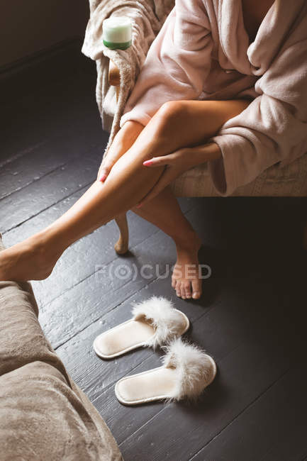 Vista ritagliata della donna che applica la crema sul corpo in camera da letto a casa . — Foto stock