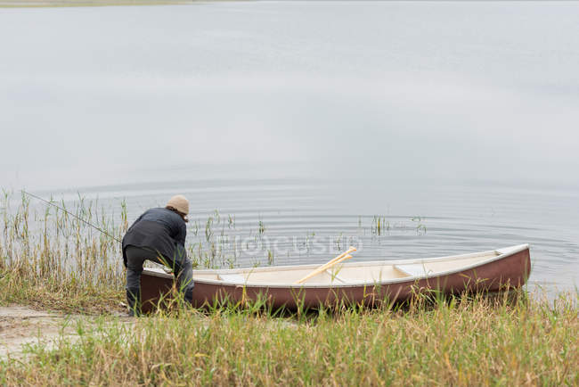 El hombre empujando su bote en el río - foto de stock