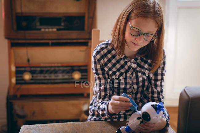 Cute girl in glasses fixing the robotic toy at home — Stock Photo