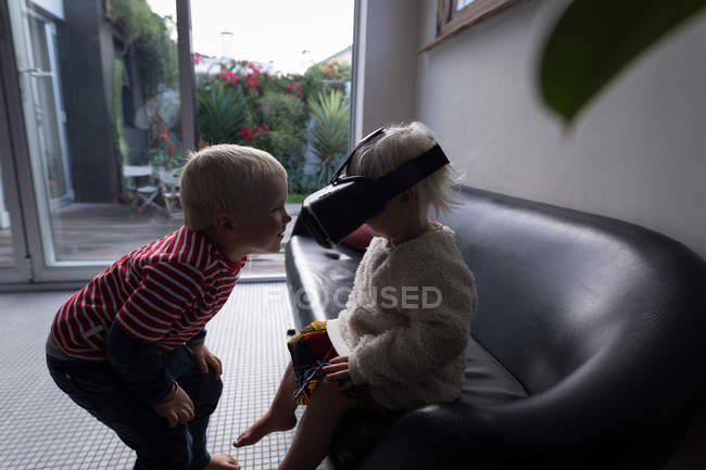 Братья и сестры веселятся в гостиной с гарнитурой виртуальной реальности дома . — стоковое фото