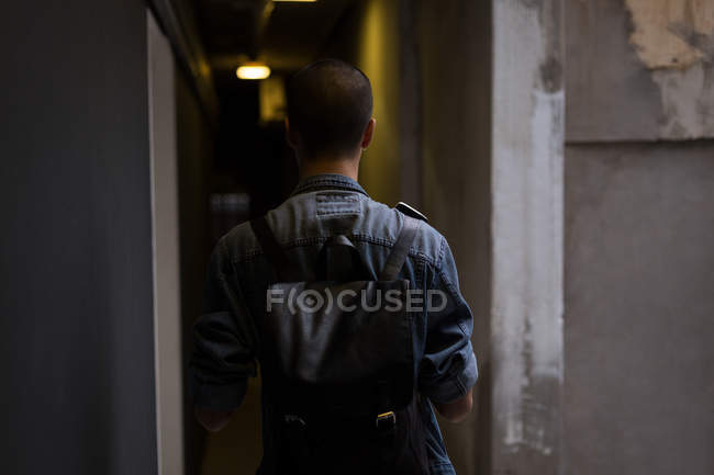 Vista trasera del joven caminando por el pasillo en el edificio - foto de stock