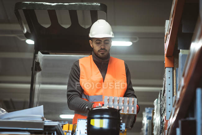 Trabalhador masculino verificando parte da máquina na fábrica — Fotografia de Stock