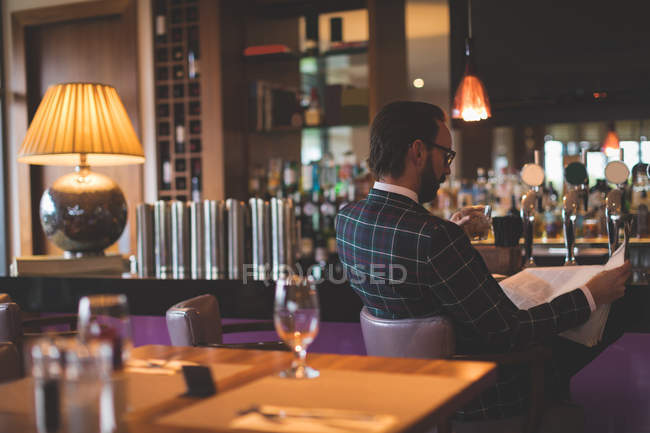 Empresário verificando documentos enquanto tem uísque no bar — Fotografia de Stock