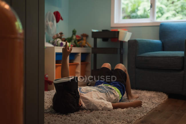 Menino usando fone de ouvido de realidade virtual na sala de estar em casa — Fotografia de Stock